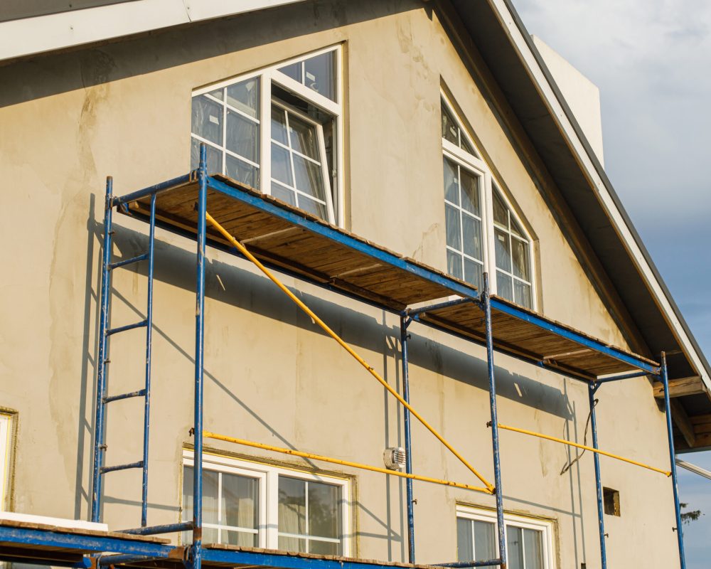 House insulation concept. Facade insulation with mineral wool, thermal improvement and energy saving. Modern farmhouse renovation, scaffolding platform and stone wool covered with plaster